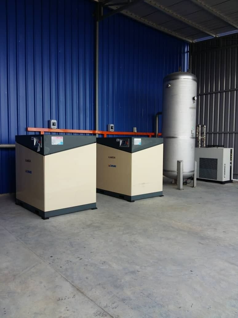 Two rotary screw compressors with a vertical air receiver installed in a factory unit
