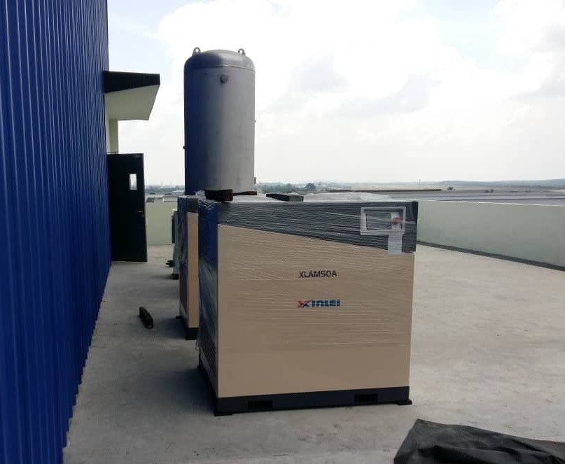 Xinlei XLAM50A rotary screw compressor installed on a factory rooftop with a vertical air receiver